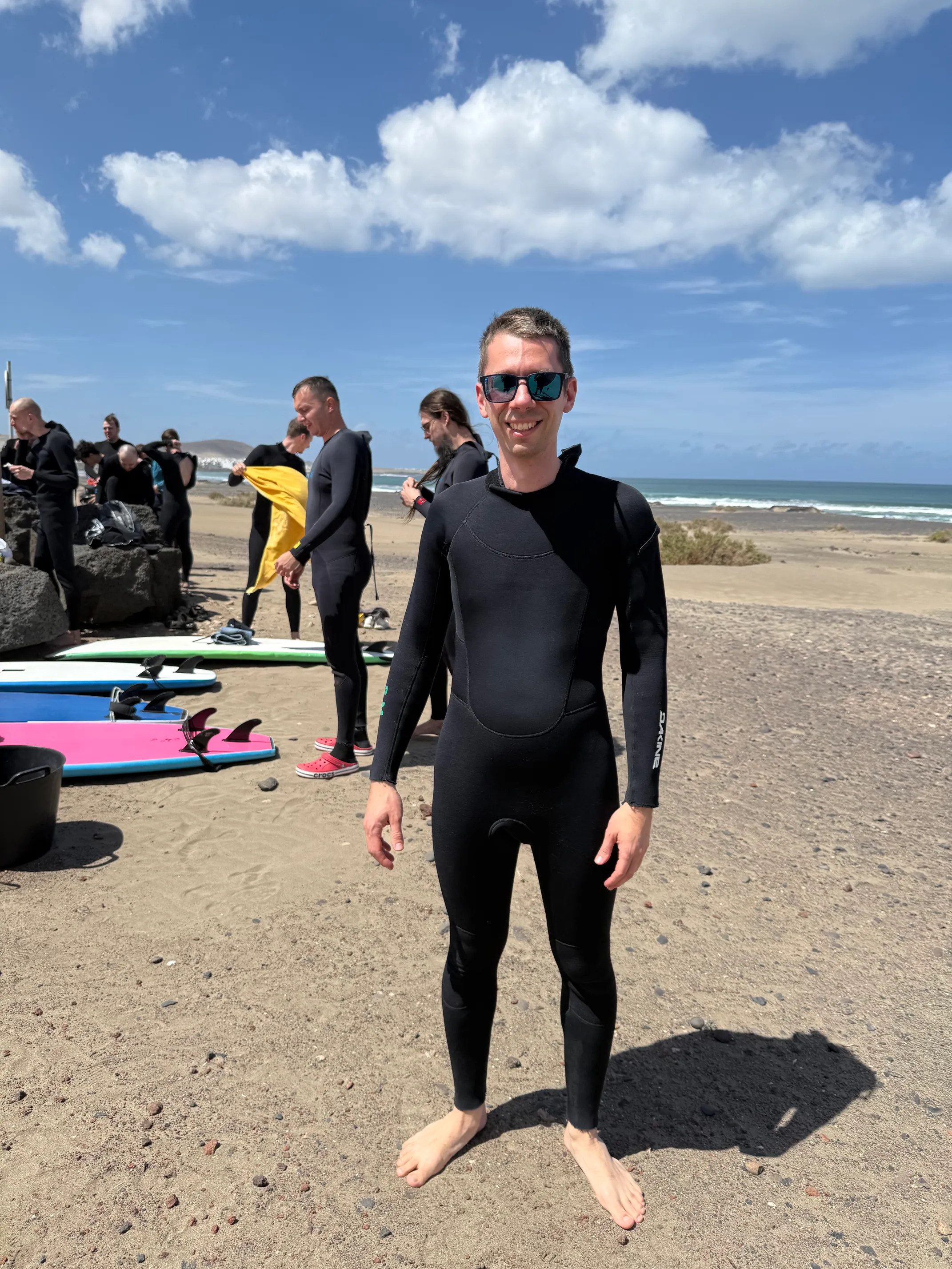 I, standing on Famara Beach, with a wet suit on, reading for surf lessons